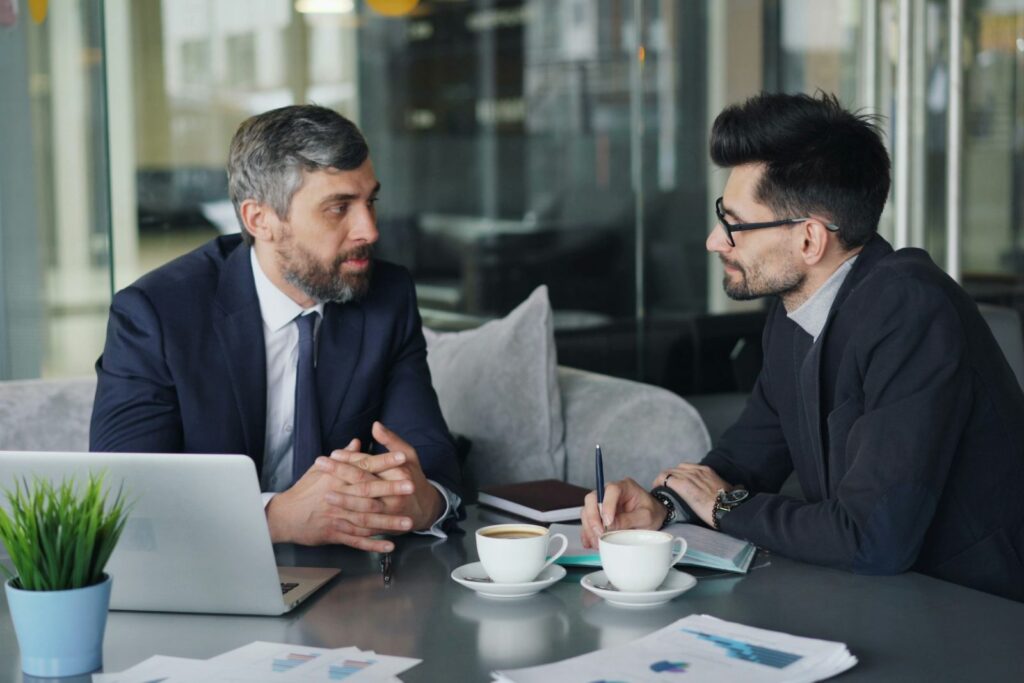 Two business partners meeting at a table with a laptop