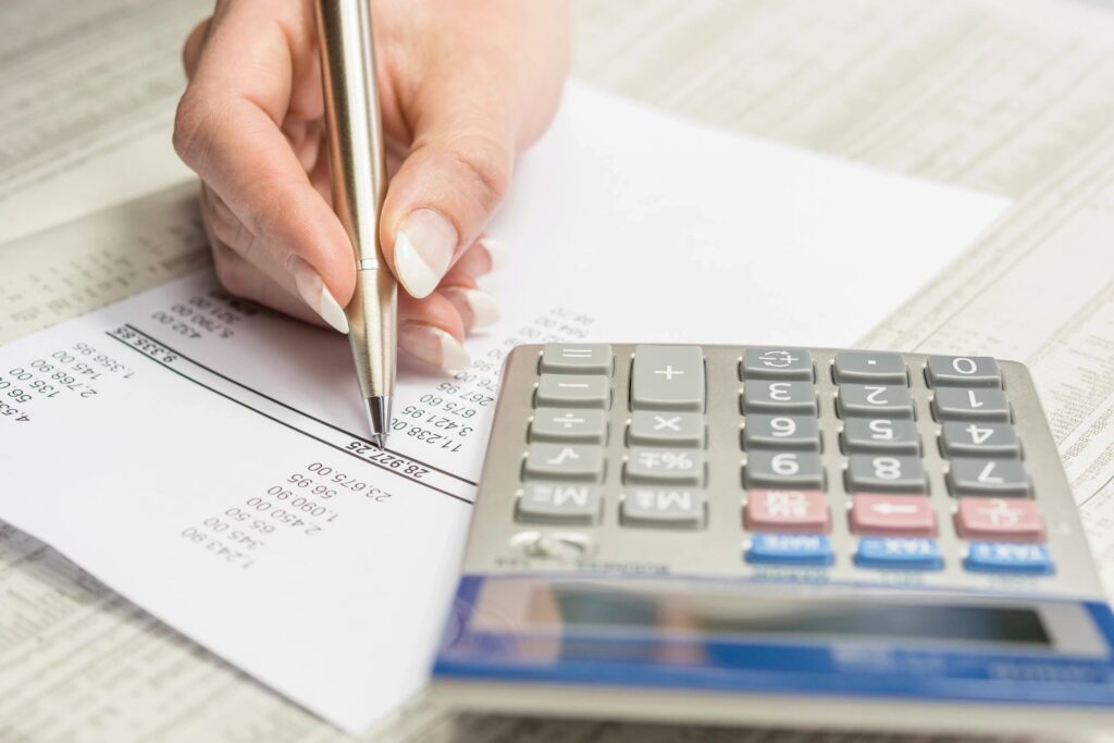 Hand reviewing a receipt with a pen and calculator