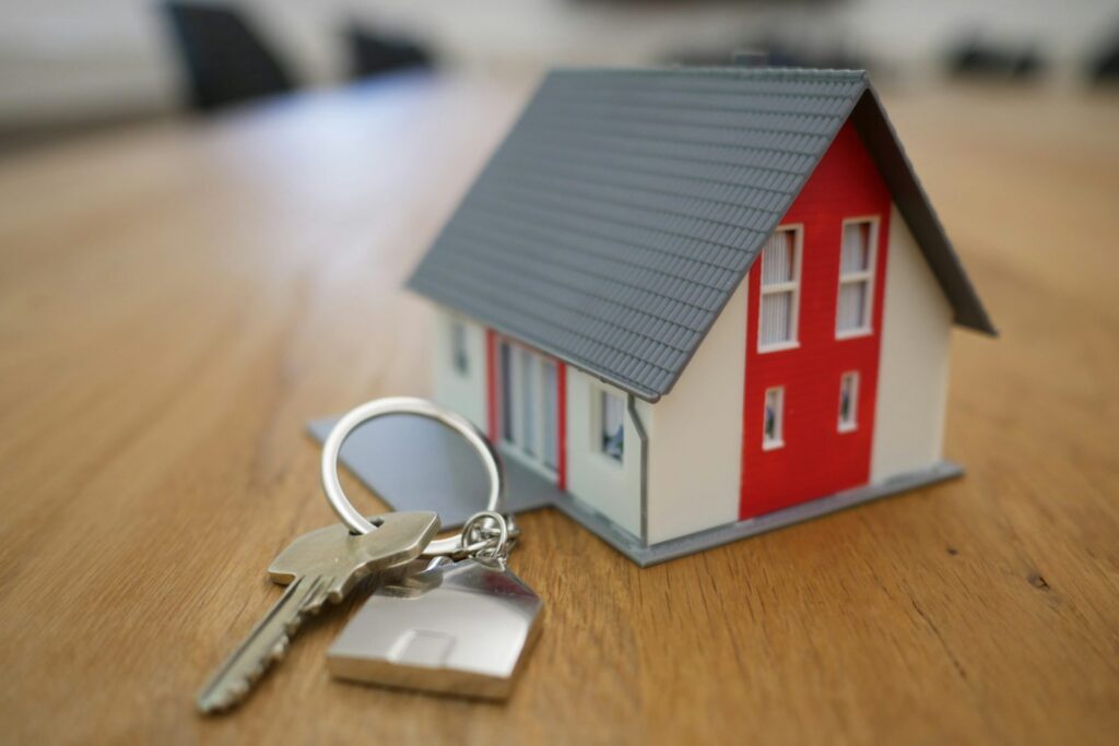 Small model house and a set of house keys on a wooden table