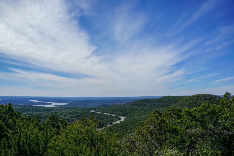 Texas Hill Country view with a winding road and a lake under a blue sky